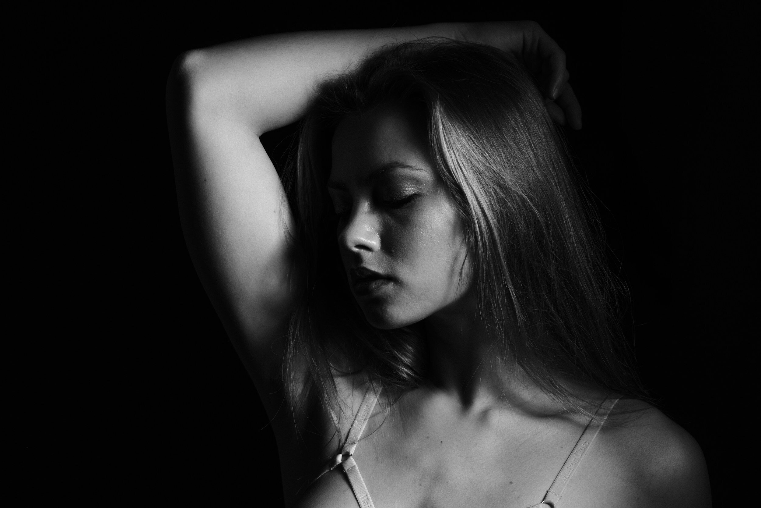 A woman with blonde hair poses in front of a dark background during a Vegas boudoir experience.