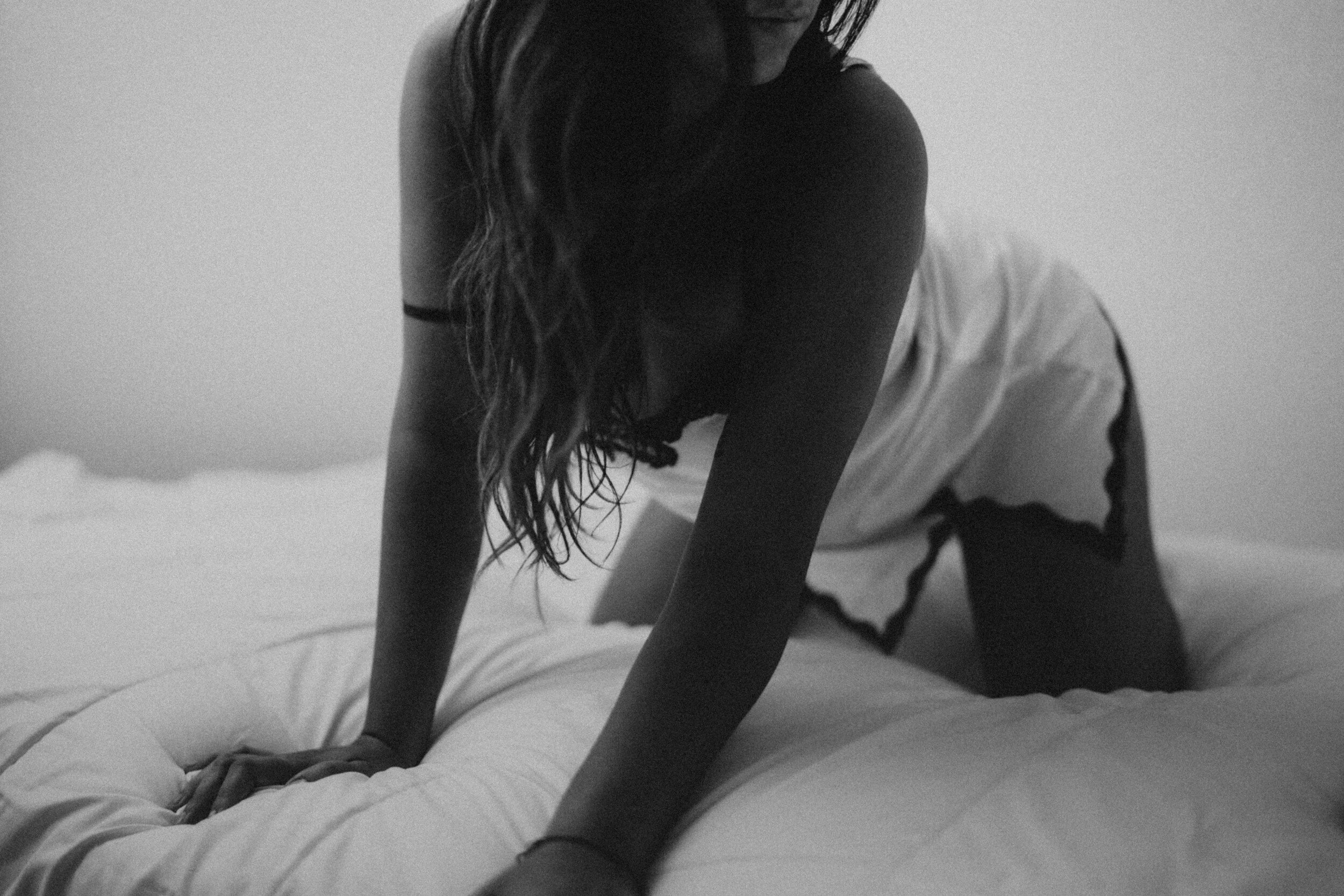 A woman poses on white sheets during a Vegas boudoir experience.