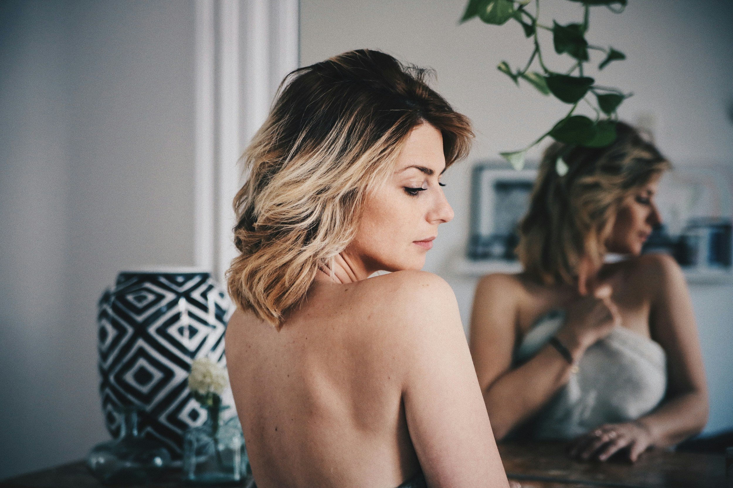 Woman with short blonde hair posing topless in front of a mirror during a Las Vegas boudoir photography session