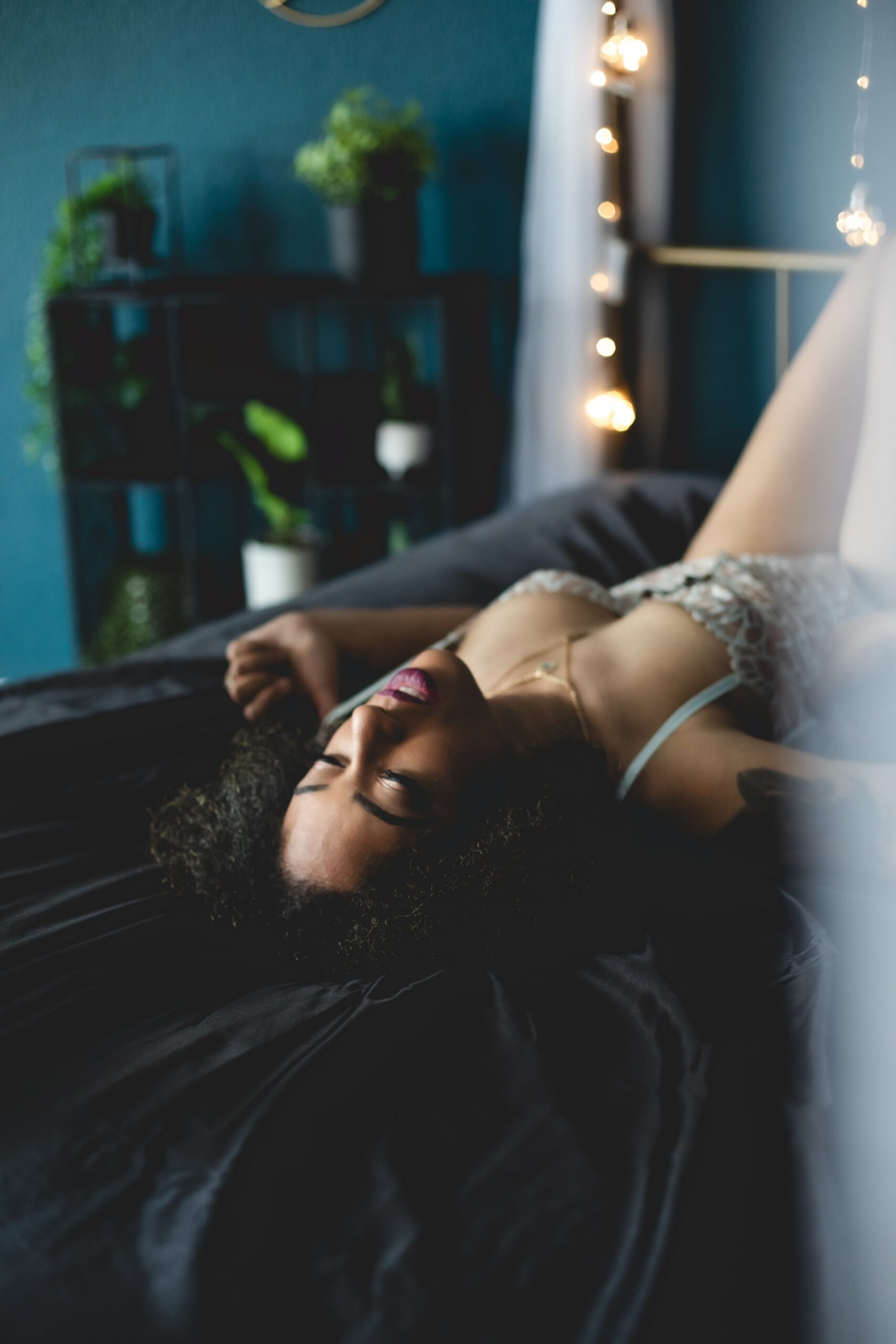 A woman poses on a bed with black sheets wearing white lingerie during a Vegas boudoir shoot