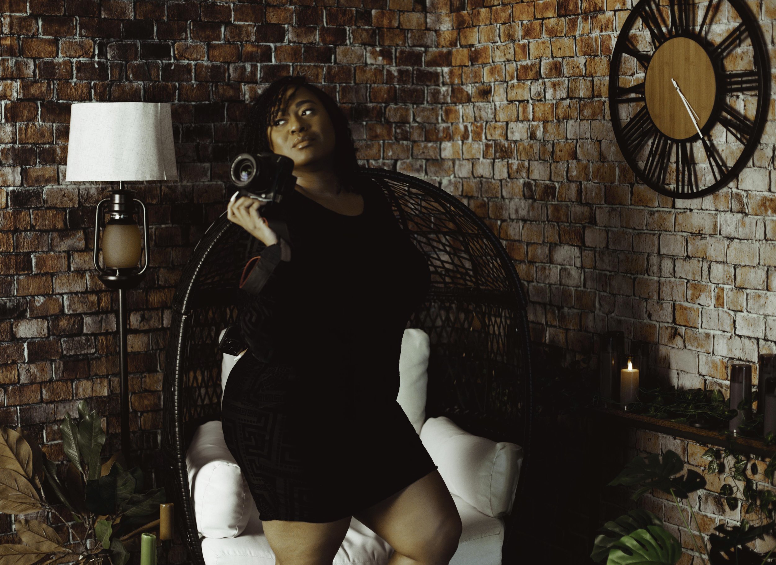 Vegas Boudoir Photographer Latasha Nicole poses in front of a brick wall holding her camera in her Vegas Boudoir Studio